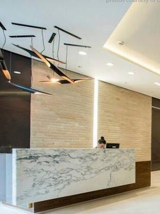 Black and gold pipe pendants on long ceiling canopies above a marble-look reception counter
