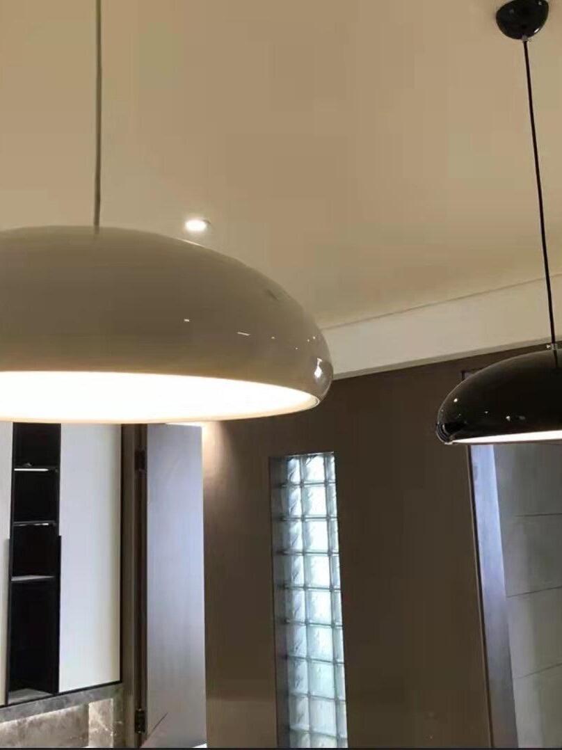 Pale dome pendant beside a black dome in an interior with tall windows