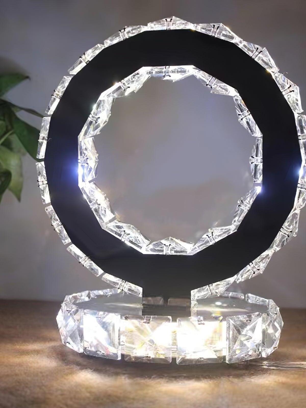 Front view of a lit reflective ring and faceted base on a pale tabletop