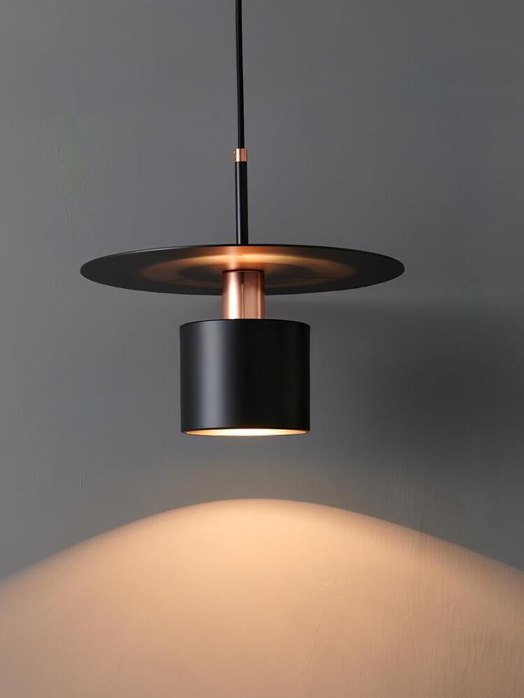 Lit black disc pendant casting light on wall