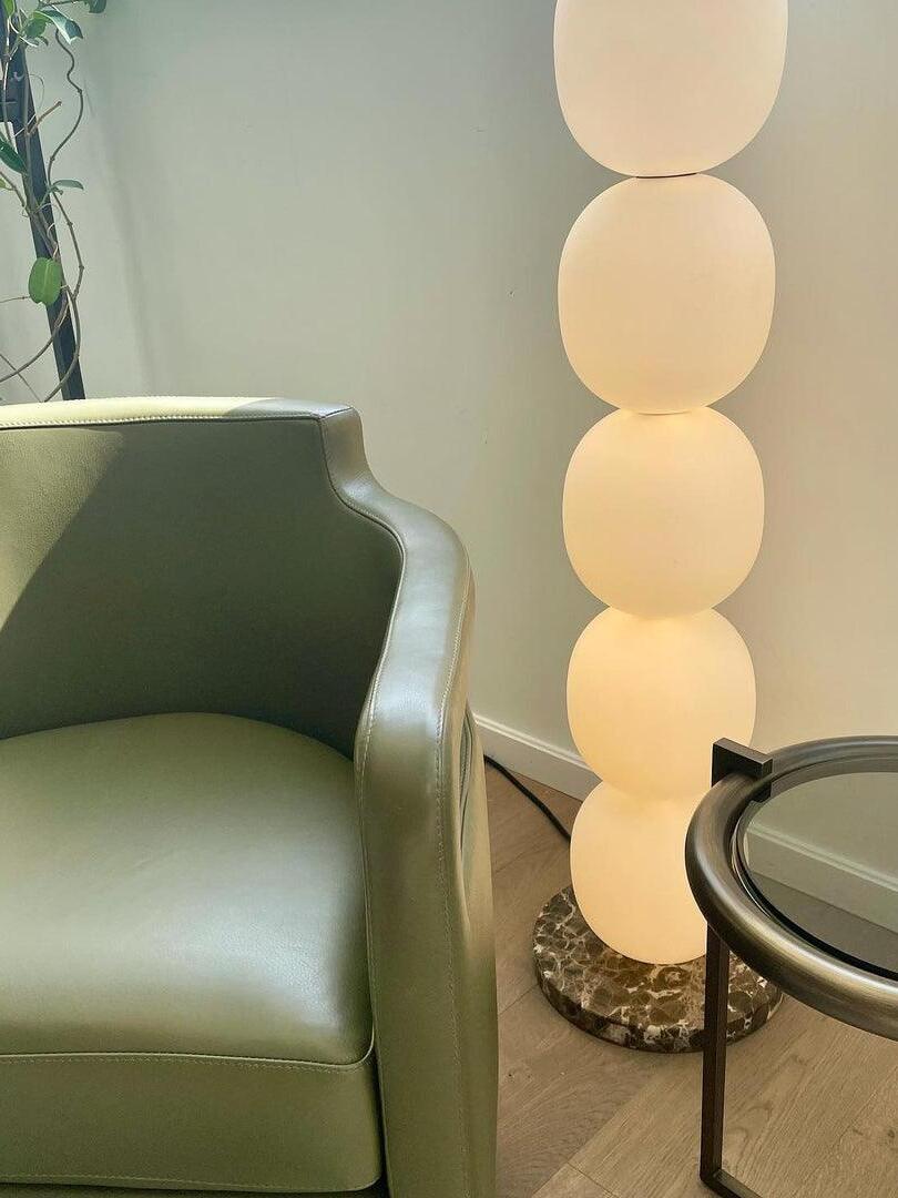 Glowing glass globe column beside green armchair