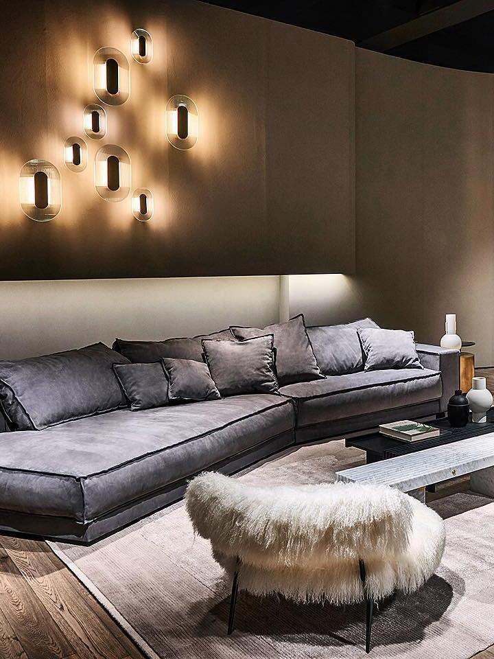 Eight elongated Button wall lights over a grey sofa with a white shaggy chair and low coffee table