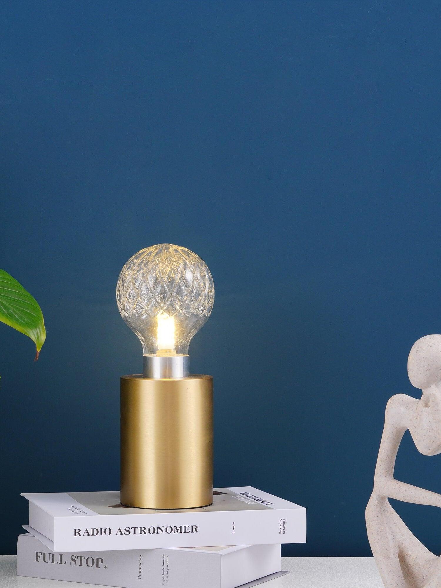 Lit patterned globe lamp on books against blue wall