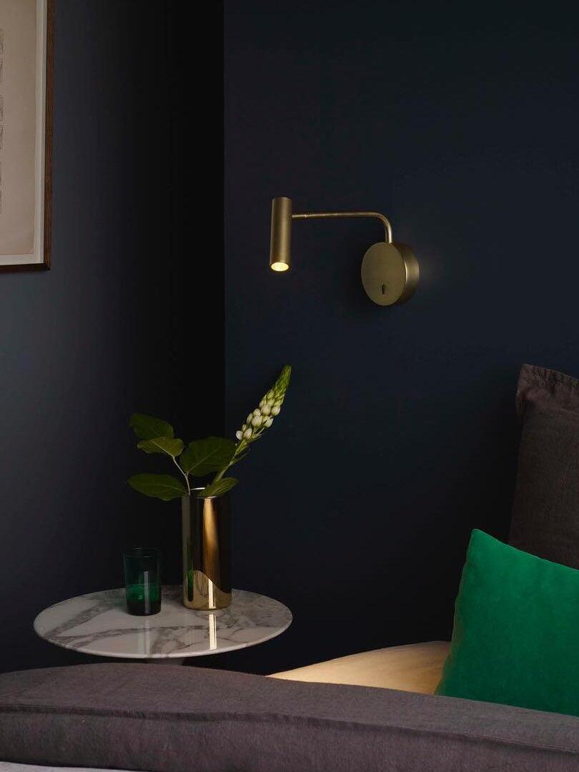 Gold-coloured wall reading light above a bedside table