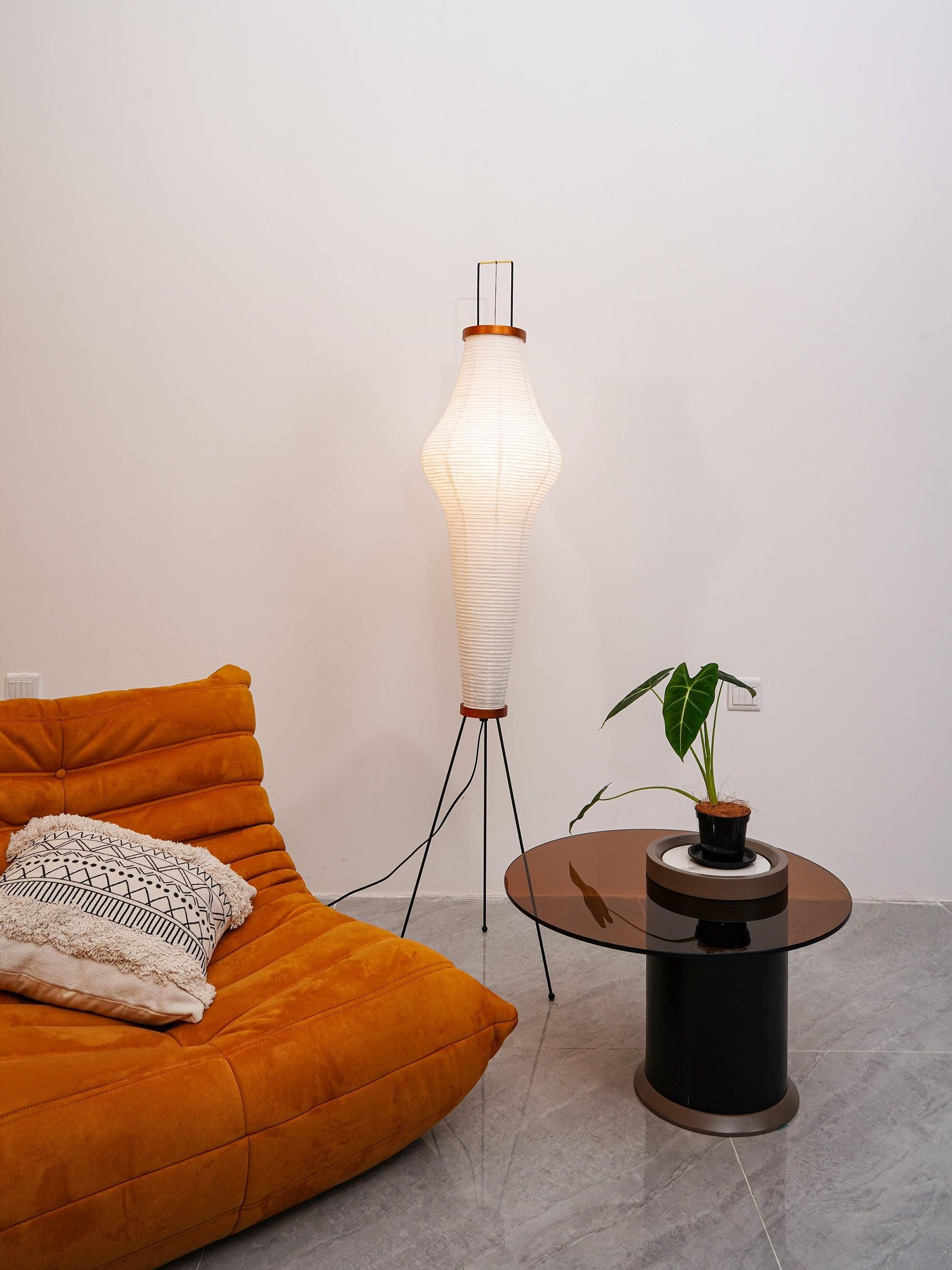 Tall paper floor lamp near orange sofa and table
