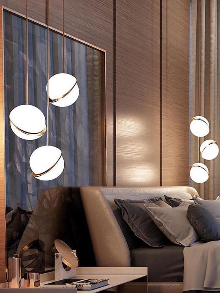 Illuminated Crescent globe pendants and their reflections beside a grey bed and bronze mirrored wall