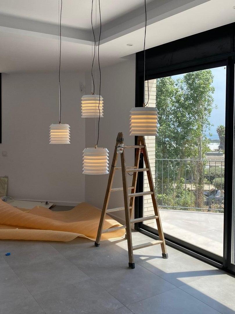 Four small white layered pendants at different heights beside large window
