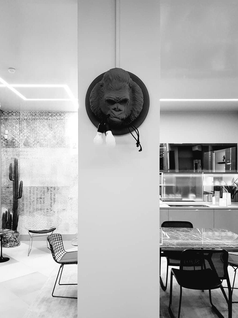 Dark gorilla wall light on pillar between seating and kitchen in monochrome view
