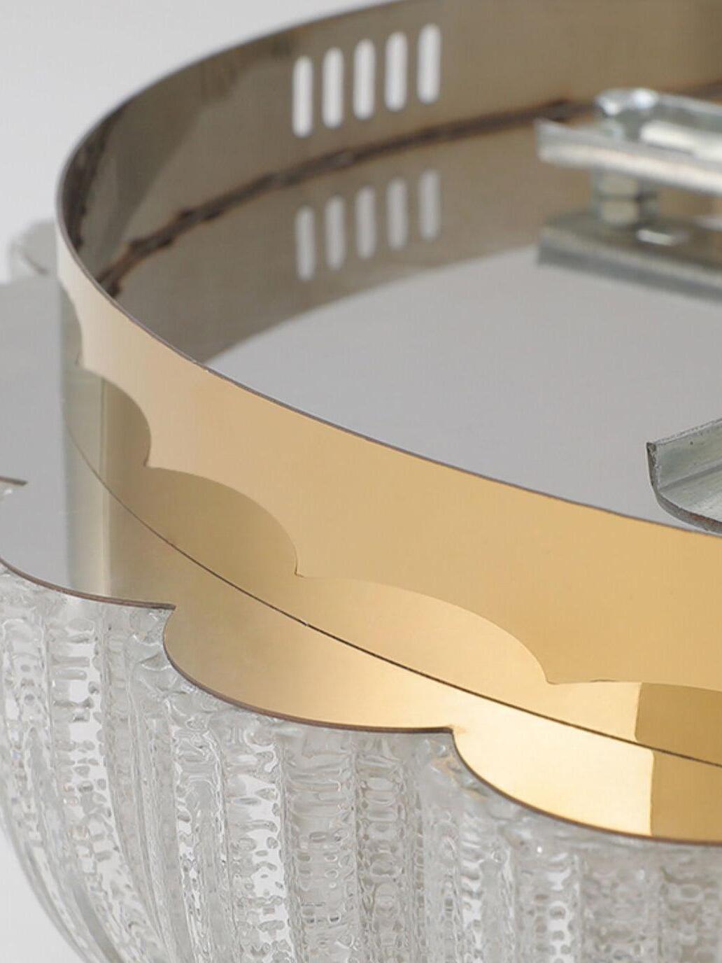 Close view of a reflective gold-tone rim with slots, inner brackets and textured glass edge