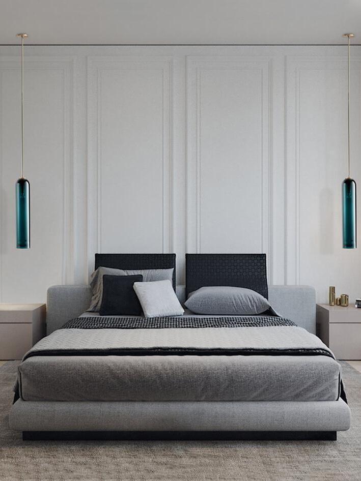 Two blue-green glass tube pendants flanking an upholstered bed, with separate ceiling canopies and bedside tables