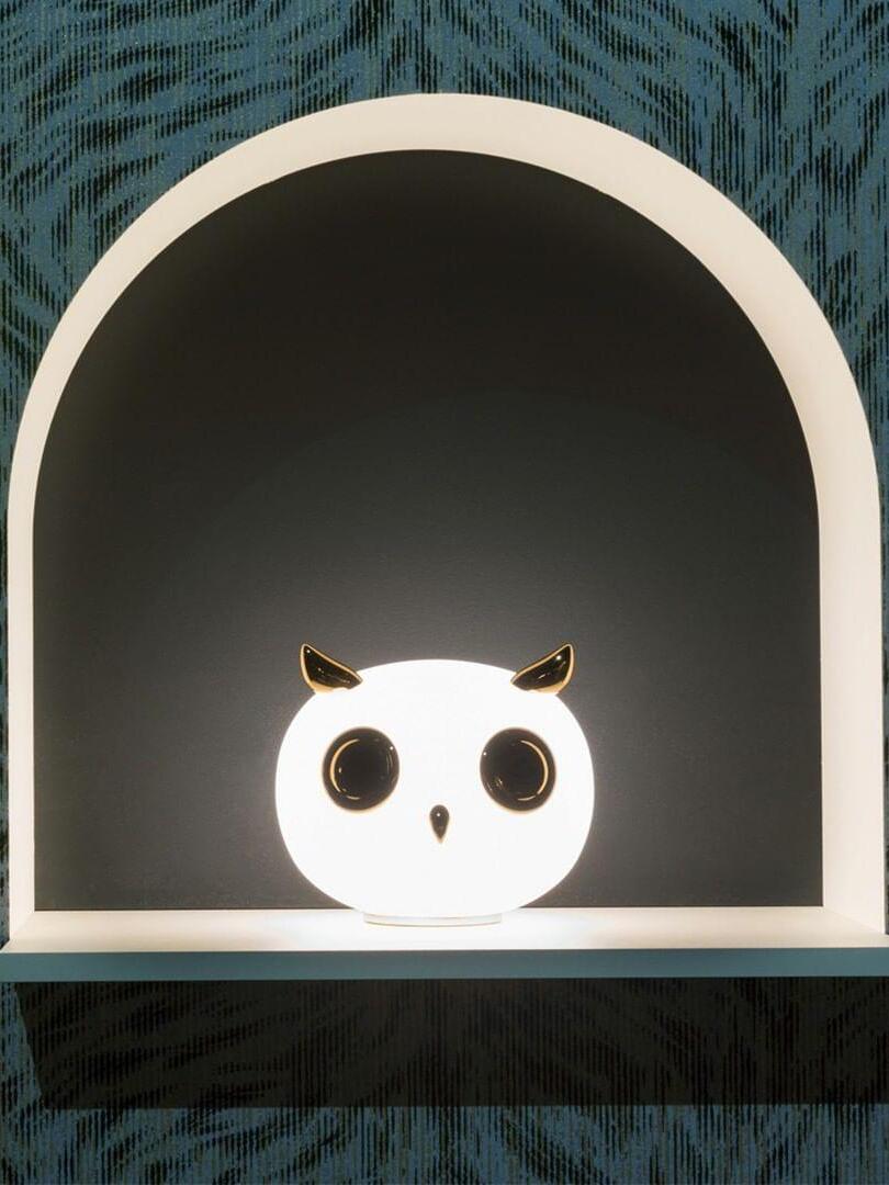 Single glowing owl in arched niche framed by patterned wall