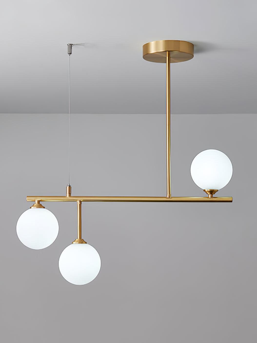 Arteriors three-globe chandelier with one globe above a brass-tone bar and two hanging below it
