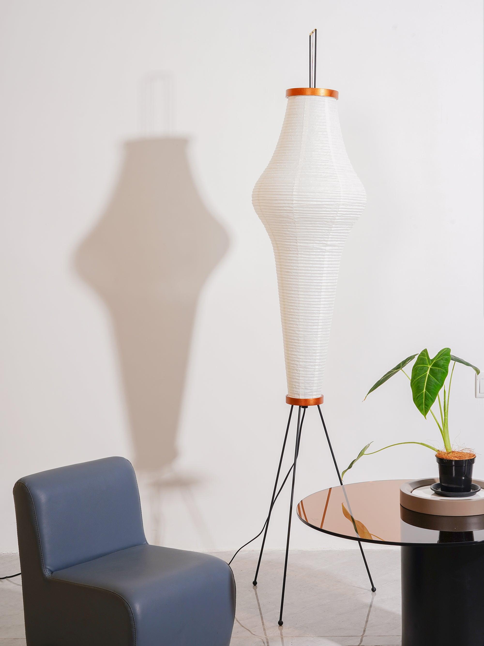 Tall shaped paper lamp casting shadow on wall