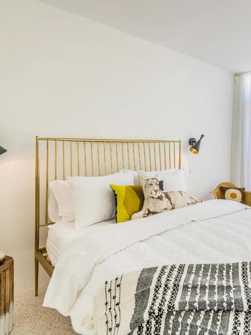 Small black cone wall light beside white bed