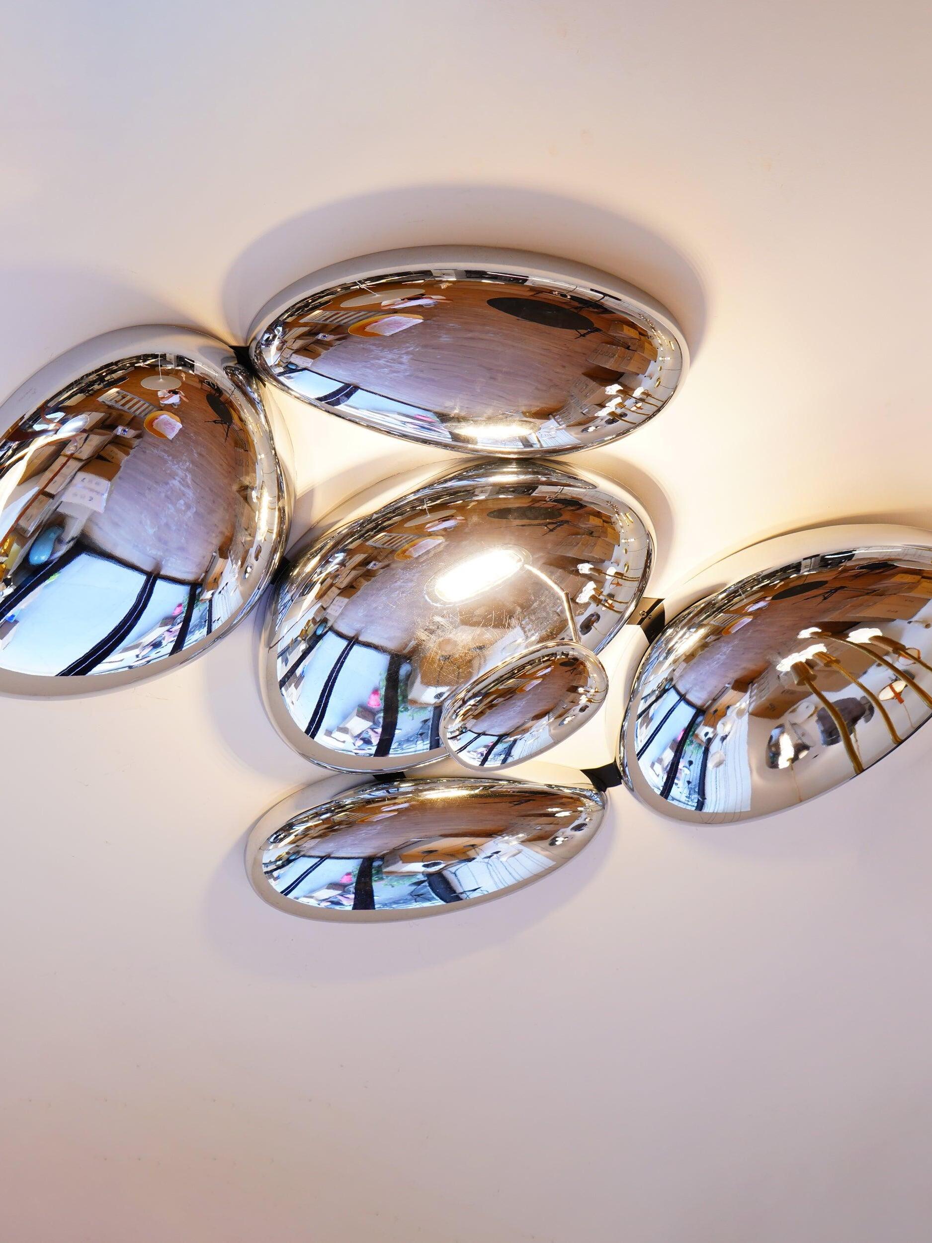 Close crop of polished irregular pebbles and narrow stem near pale ceiling