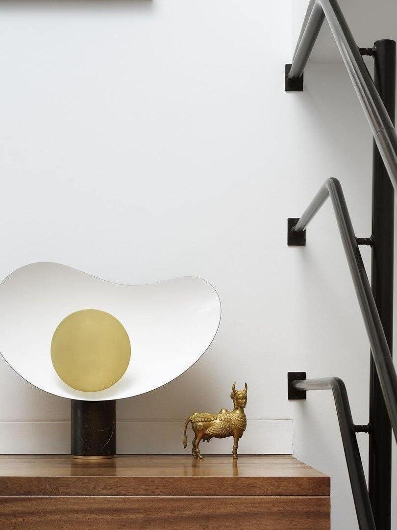 Sculptural table lamp on wooden sideboard by stairs