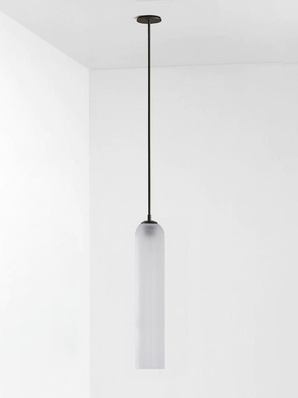 Frosted white glass Long Tube pendant with black straight rod and round black ceiling canopy on pale background