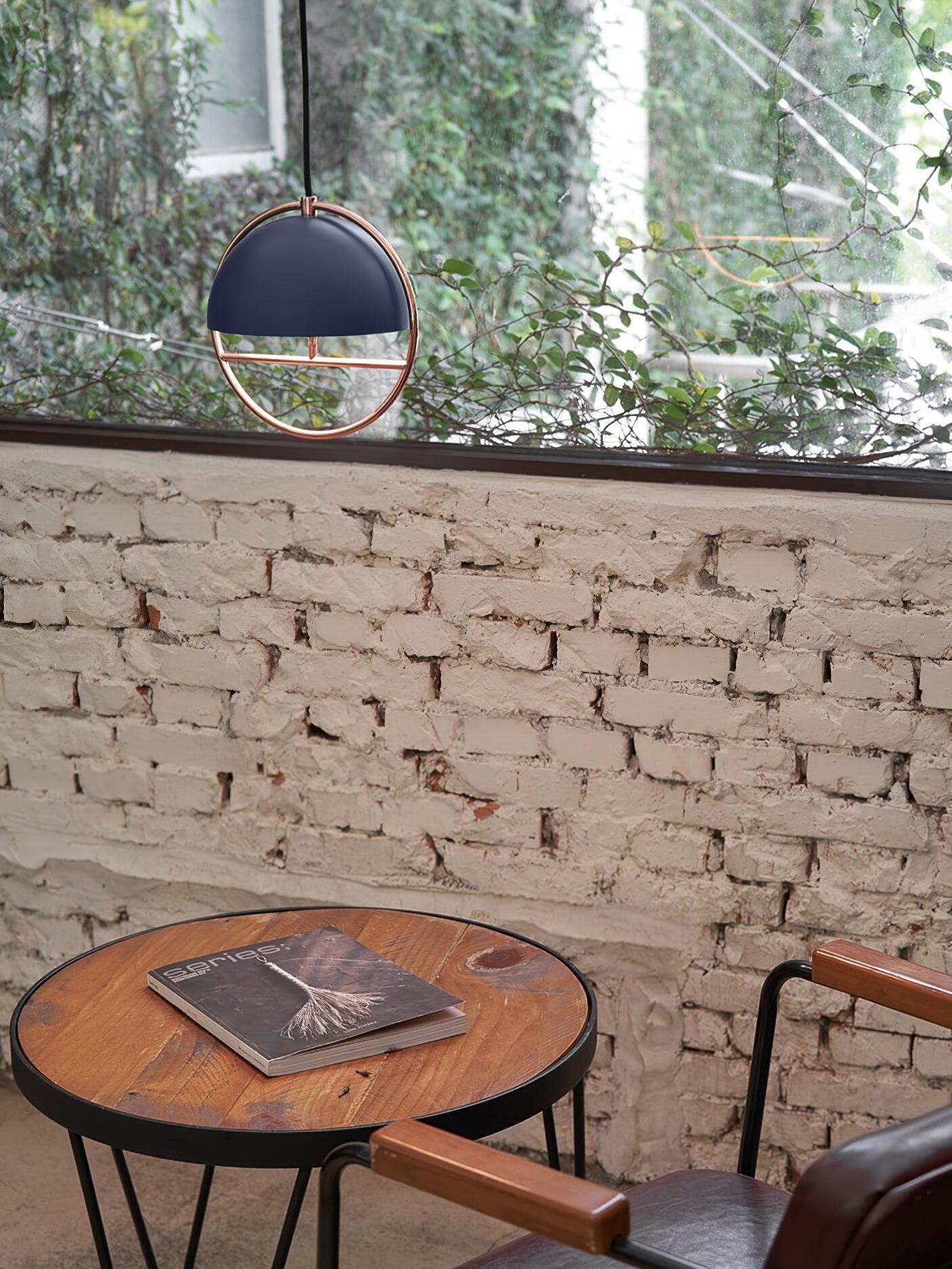Black ring pendant by brick wall and window