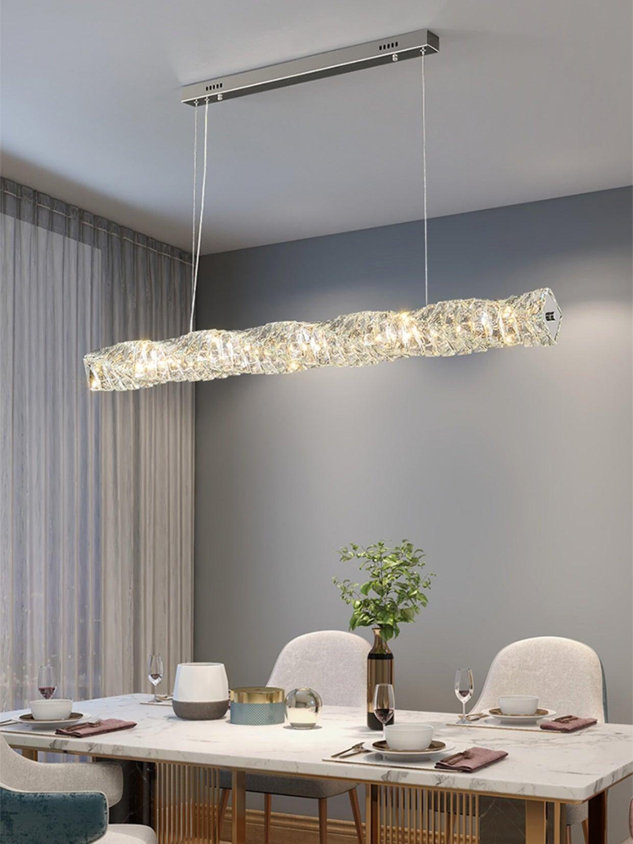 Chrome rectangular canopy and crystal bar above a pale dining table beside full-height curtains