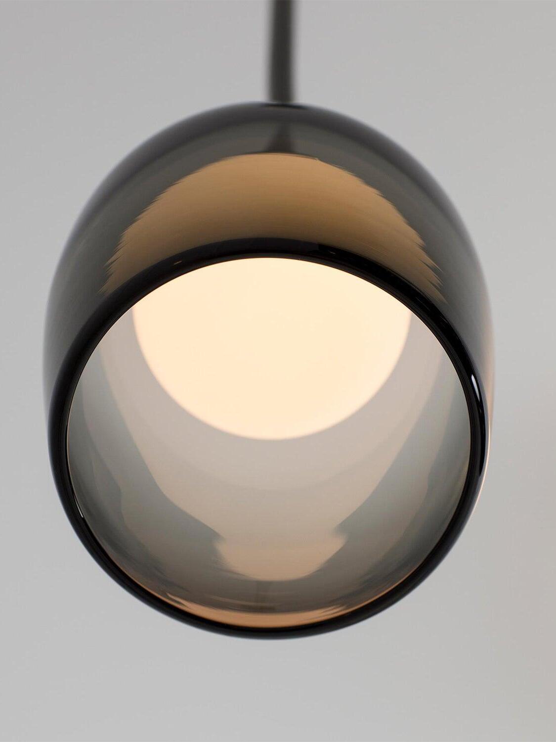 Underside view of the open gradient-black Crux glass bell and glowing inner sphere