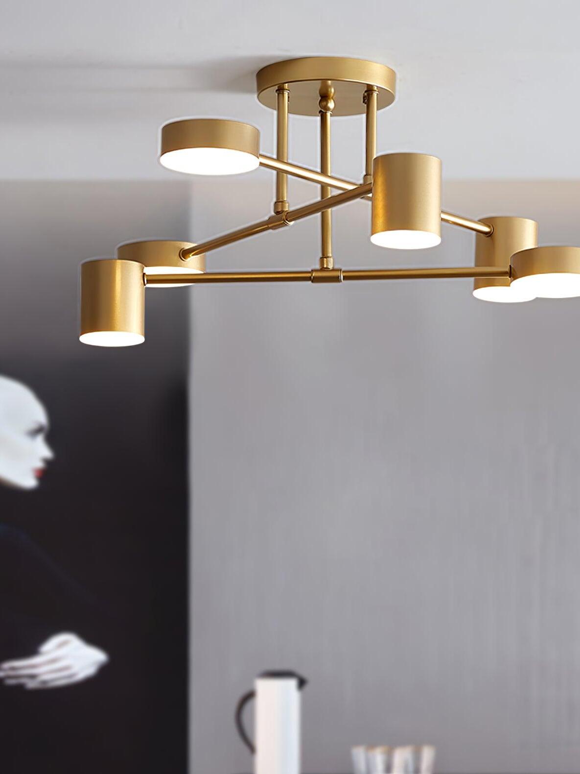Gold six-head ceiling light above gray walls, black portrait artwork and a partly visible jug and cups