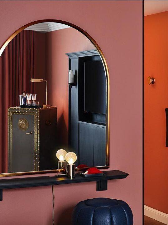 Two small globe lamps beneath round mirror against red wall