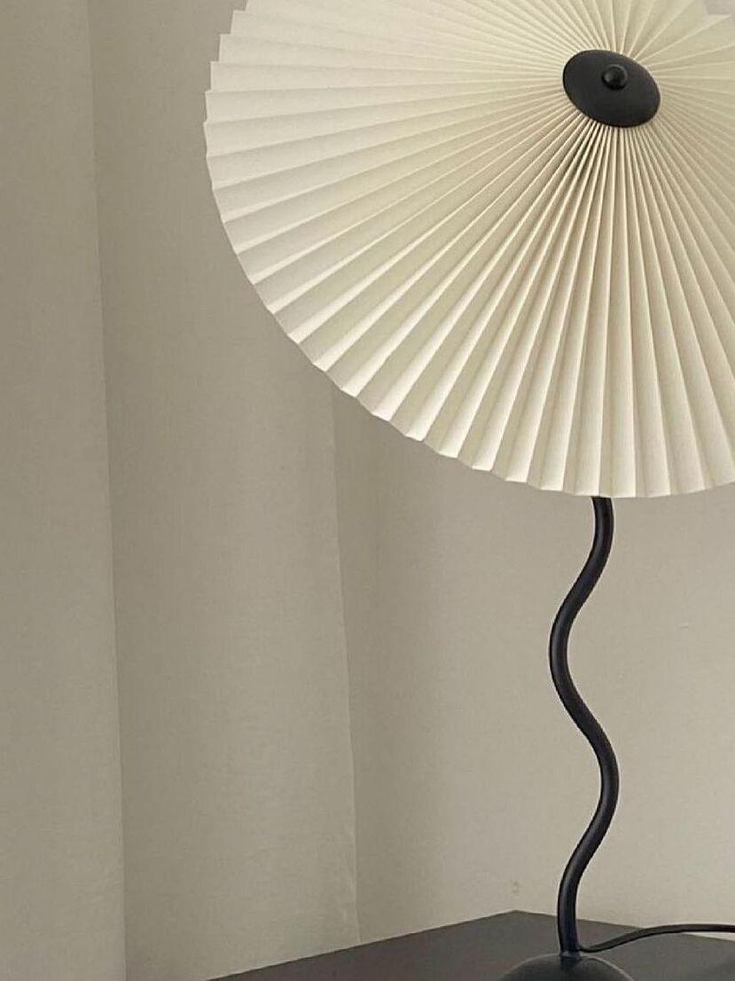 Close view of pale radial shade folds, black top fitting and wavy stem