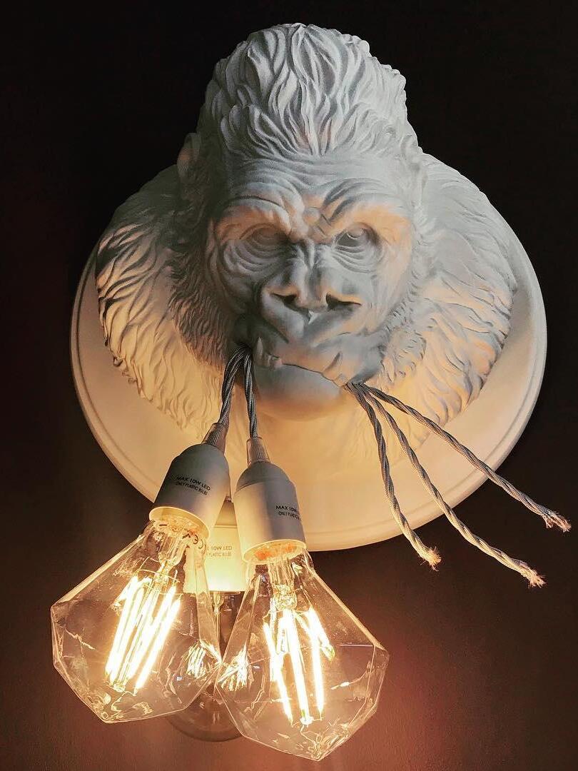 White gorilla relief with three warm glowing elongated bulbs on dark background
