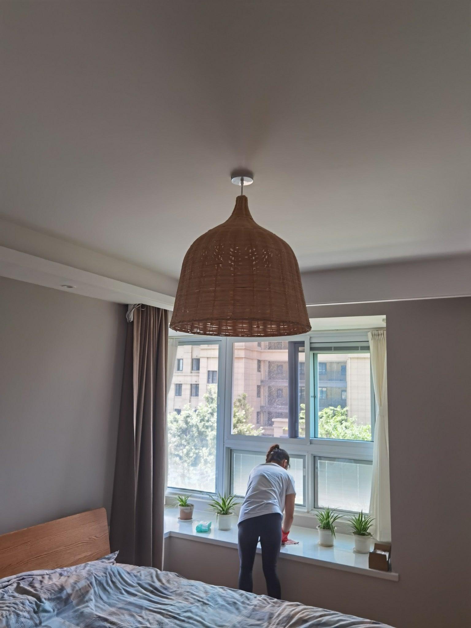 Rattan pendant above a bed near a window