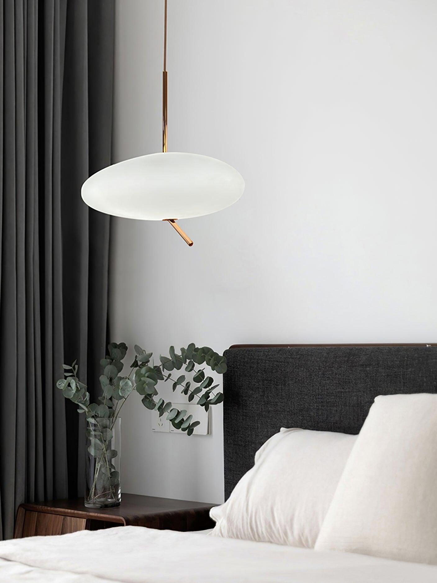 White pendant beside a bed, gray curtains and a leafy plant