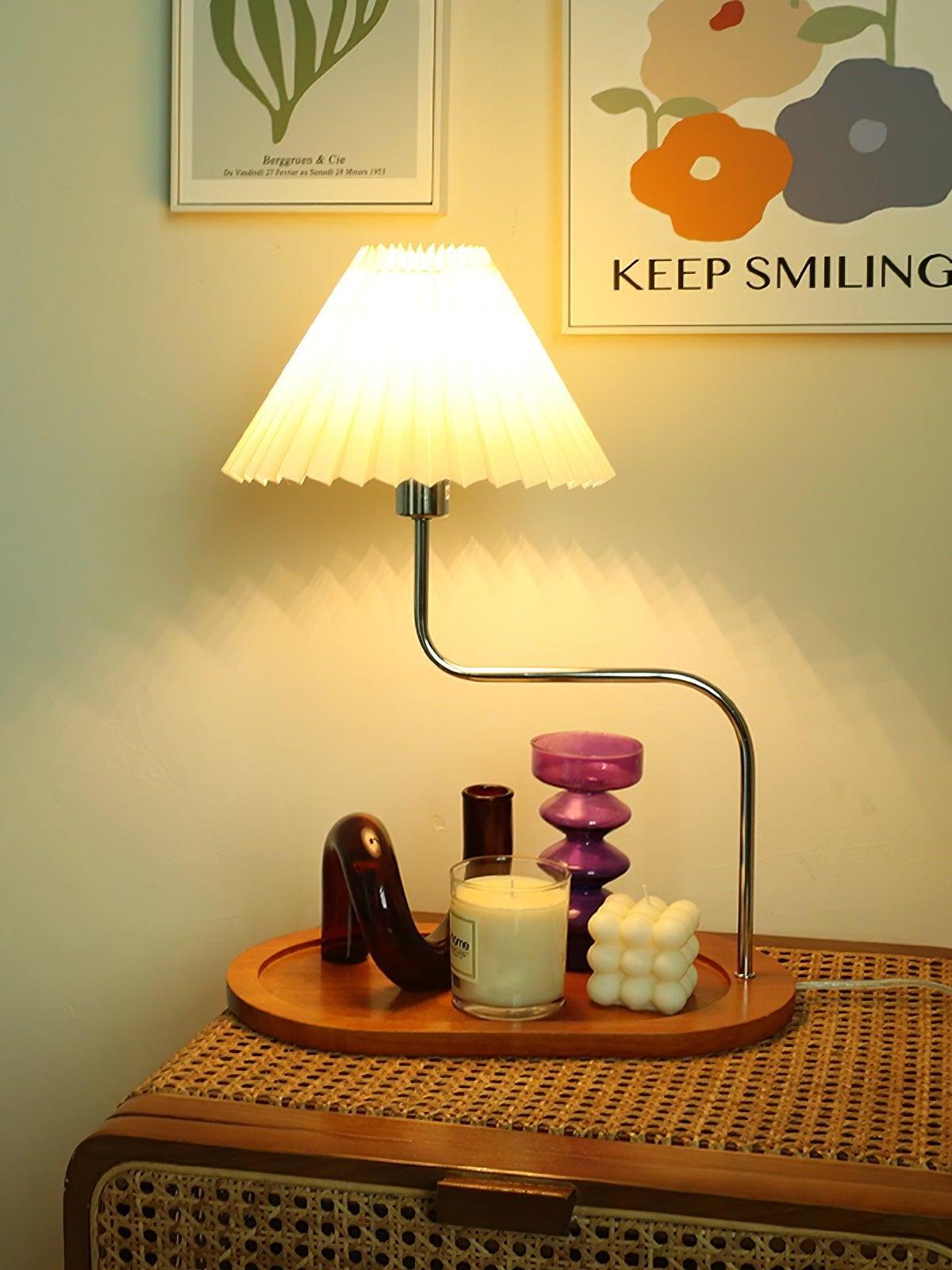 Lit pleated-shade lamp on a cabinet below wall art