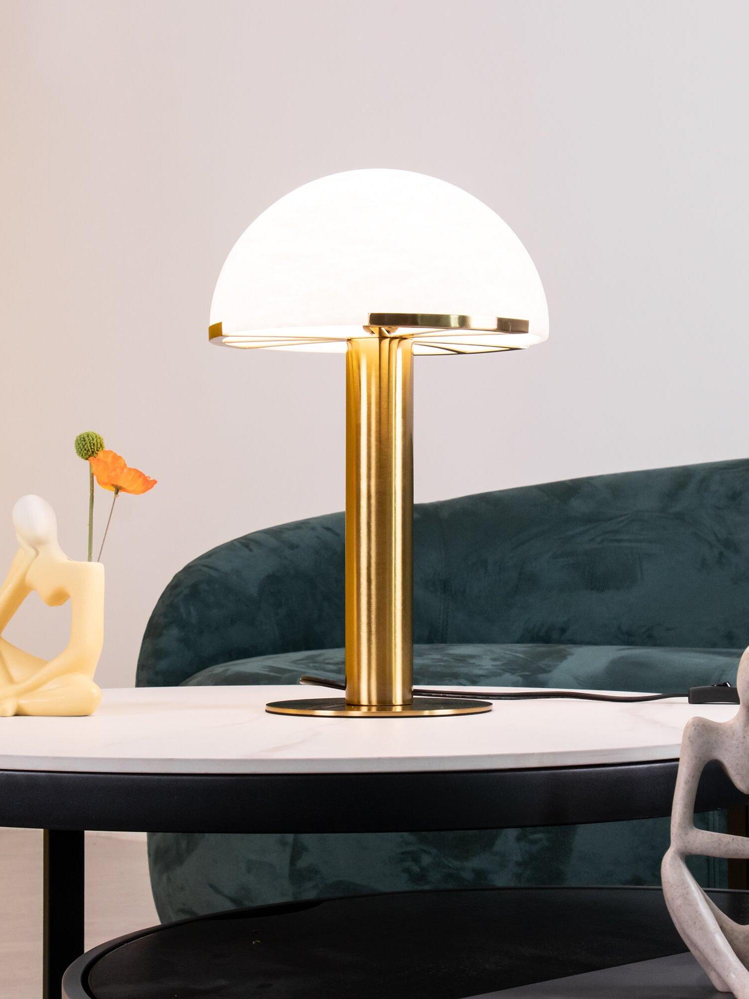 Lit Gold dome lamp in front of a green sofa