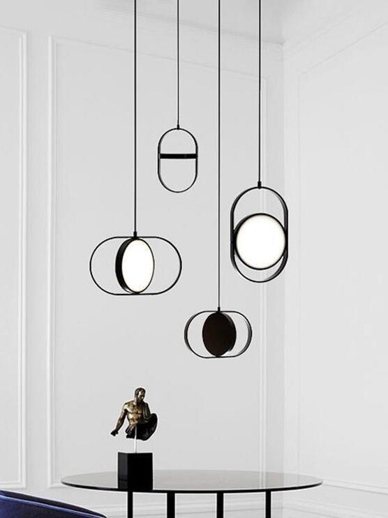 Four black disc pendants in horizontal and vertical frames above a round table with a small gold-tone statue