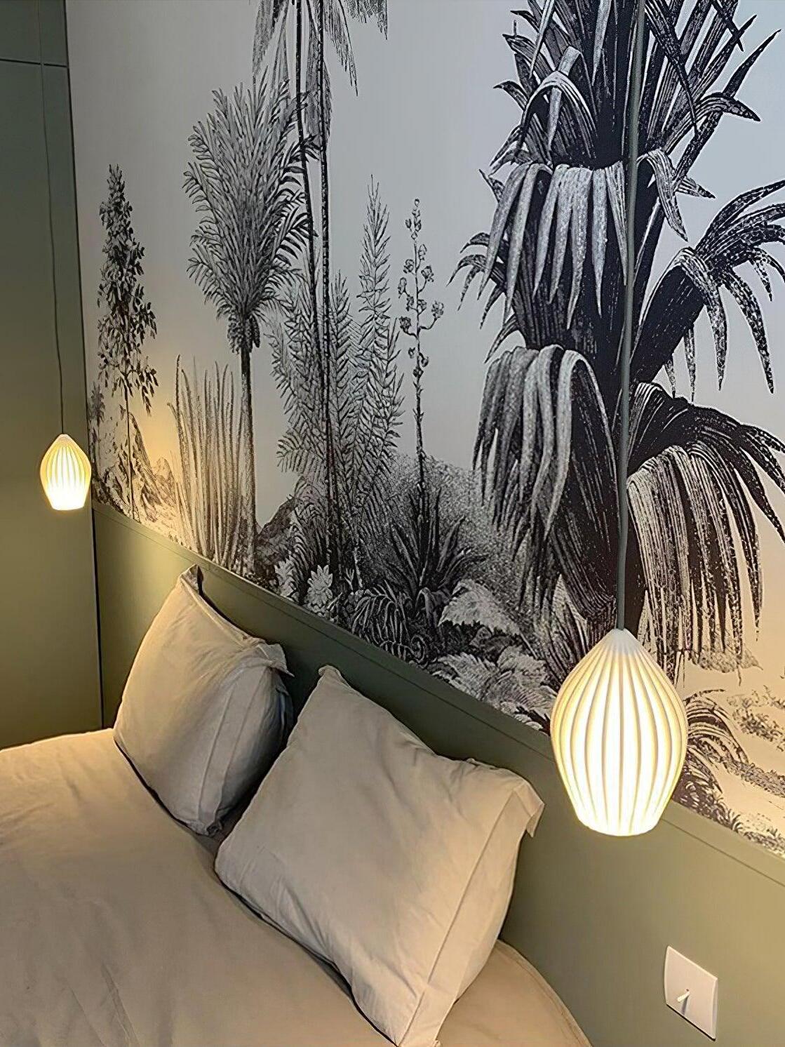 White ribbed pendant shades beside a bed with a botanical mural