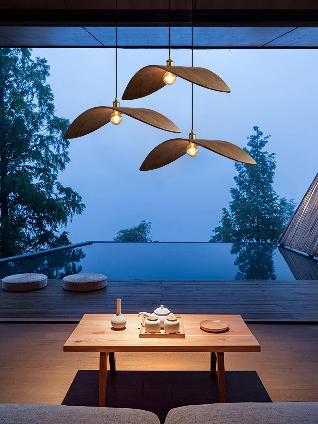Three separate curved pendants above a table facing an open terrace and trees at dusk