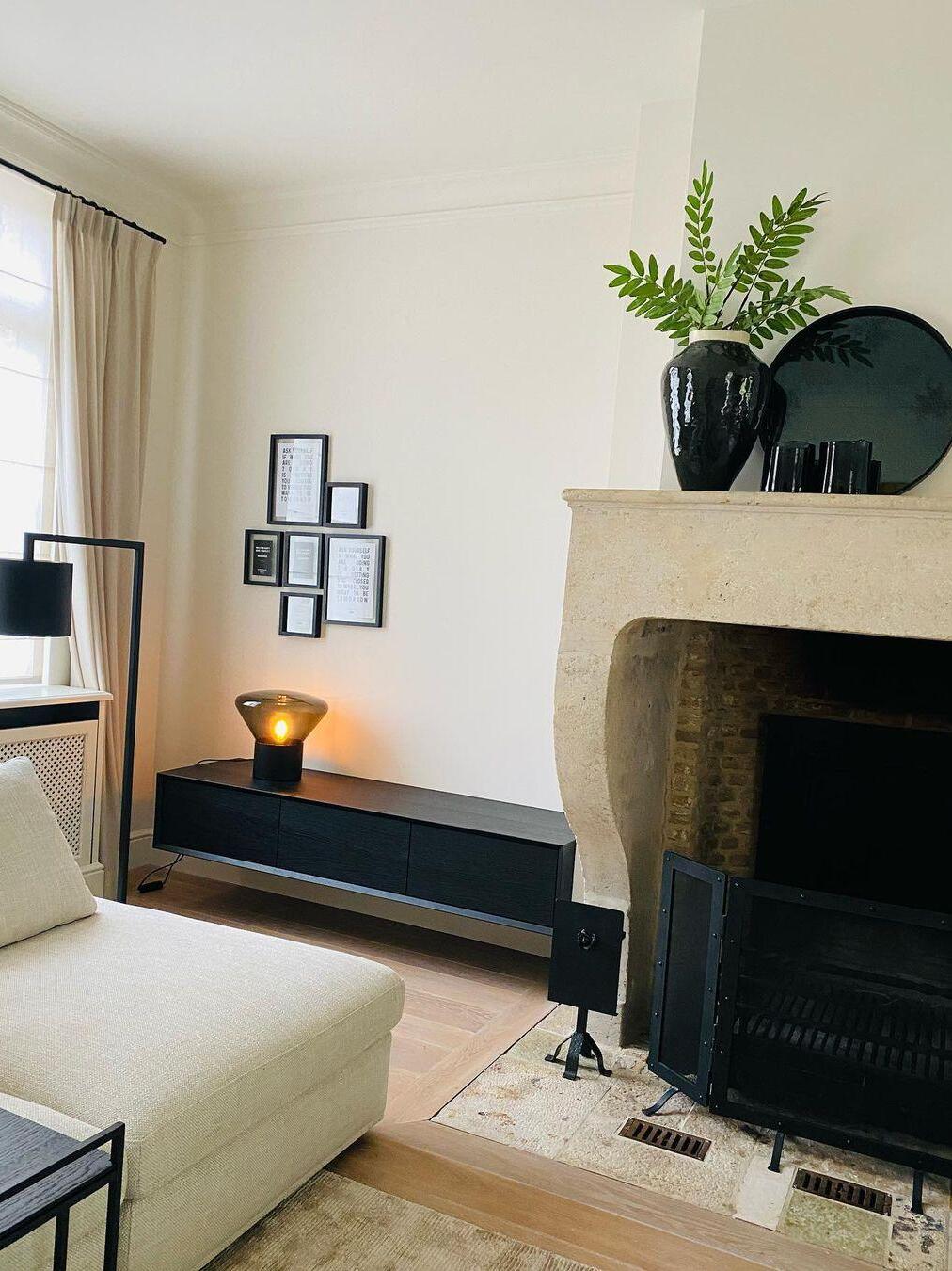 Living room with amber-lit lamp on low black console beside fireplace and sofa