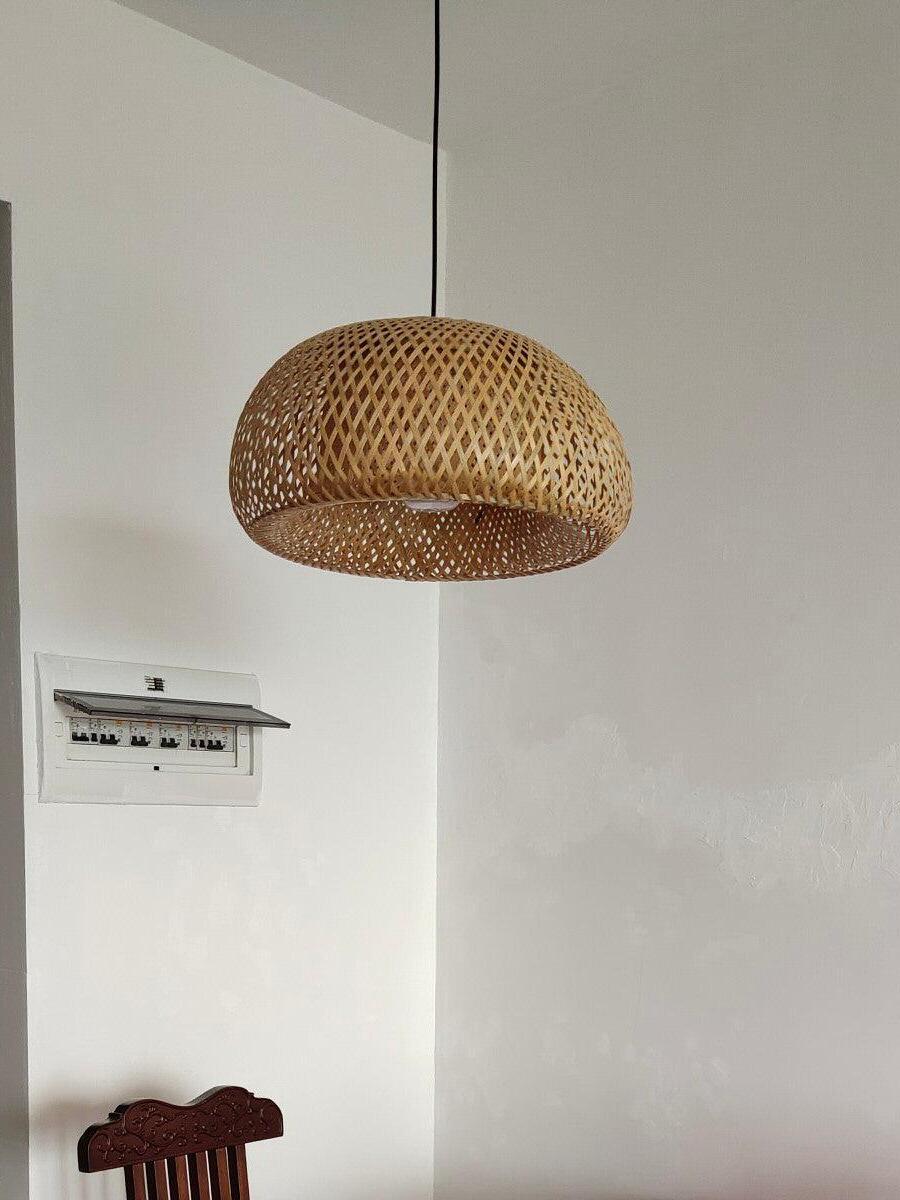 Natural woven pendant above chair against pale wall