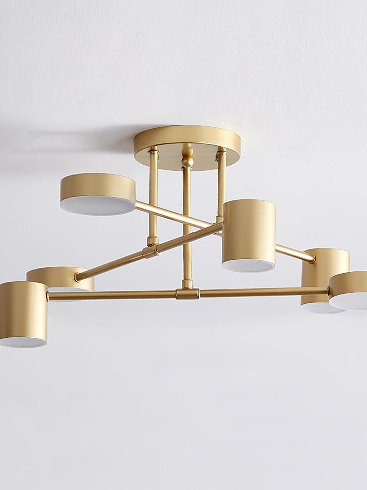 Close view of a gold six-head ceiling light with pale unlit round faces, alternating cylinder and shallow drum housings