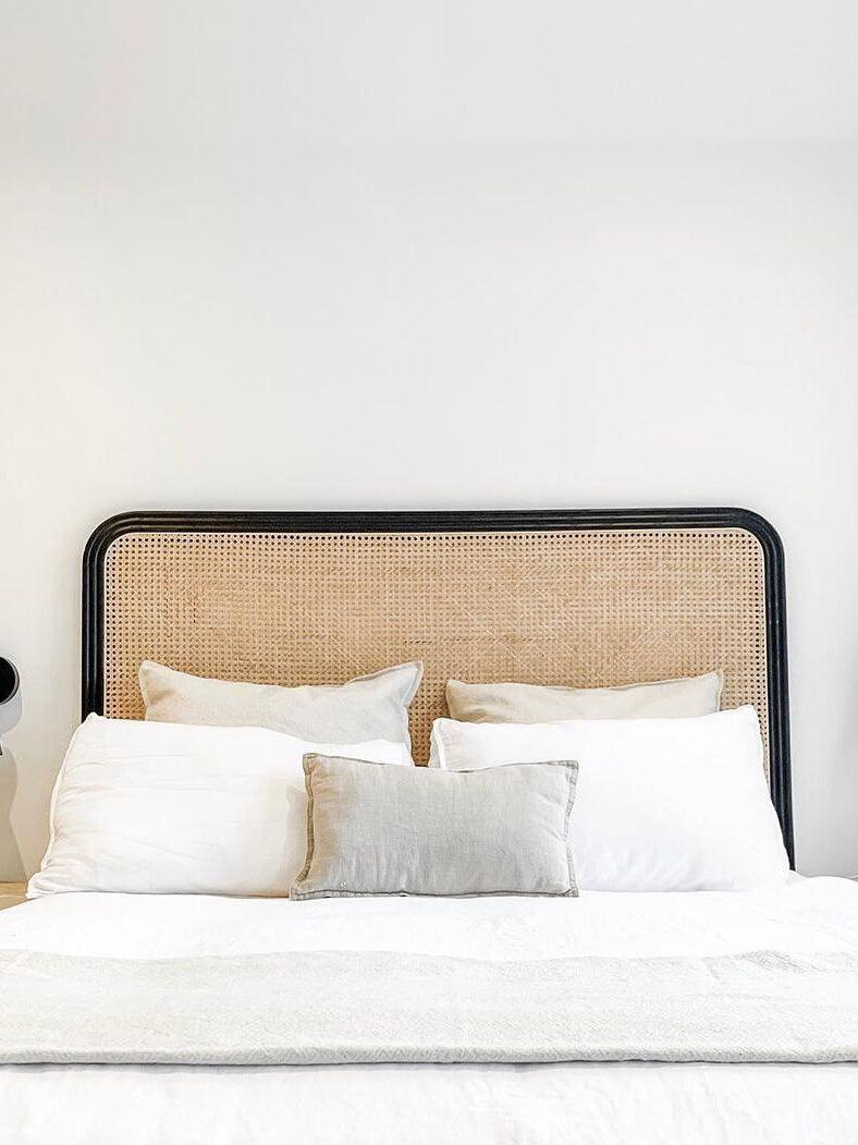 Bed and woven headboard with dark wall fixtures at frame edges