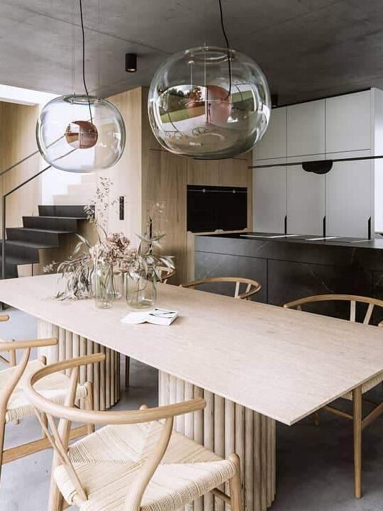 Rounded glass pendants above a pale table by a staircase