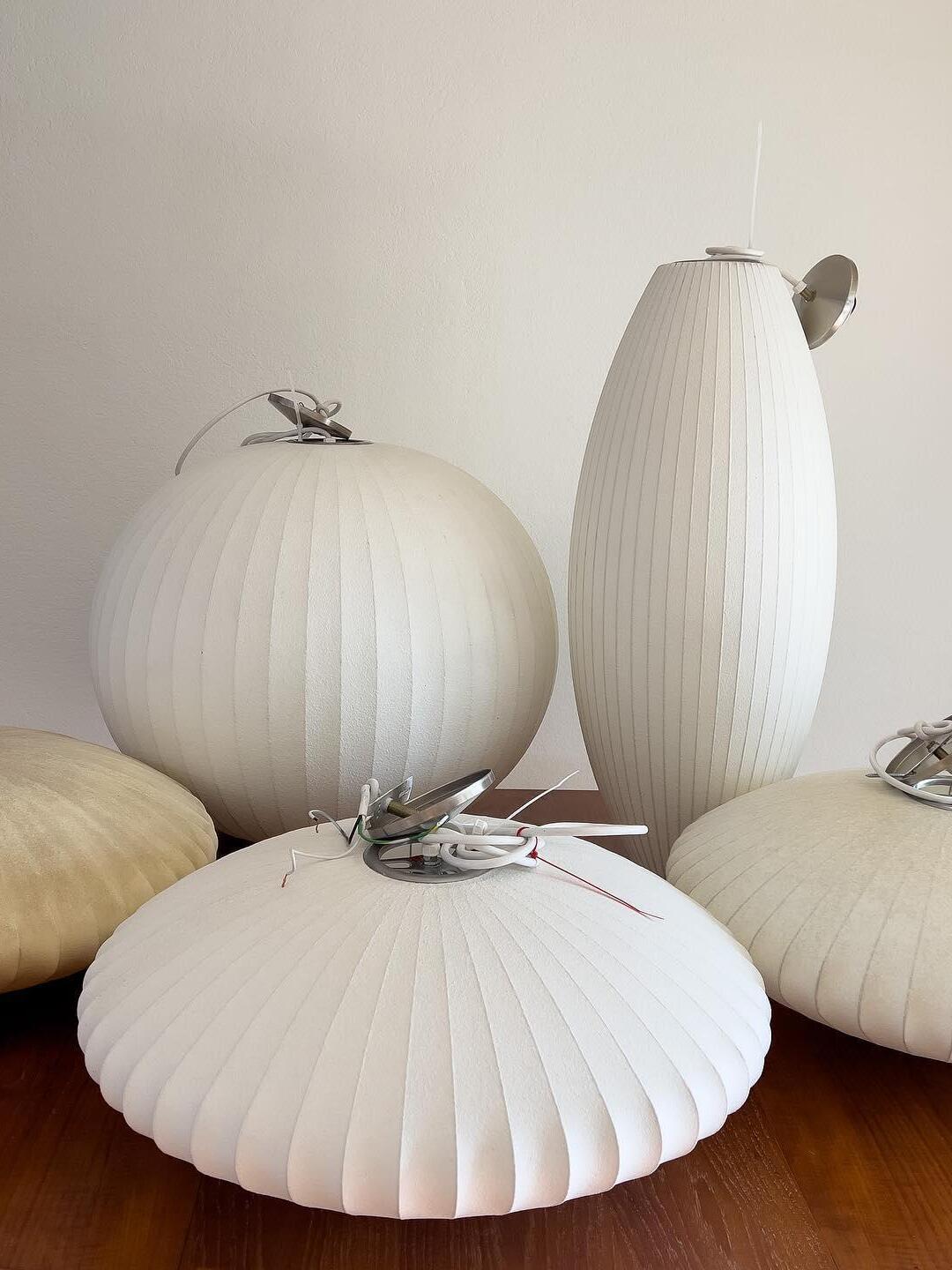 White broad, round and tall ribbed shades resting together on a table with coiled cords and metal fittings