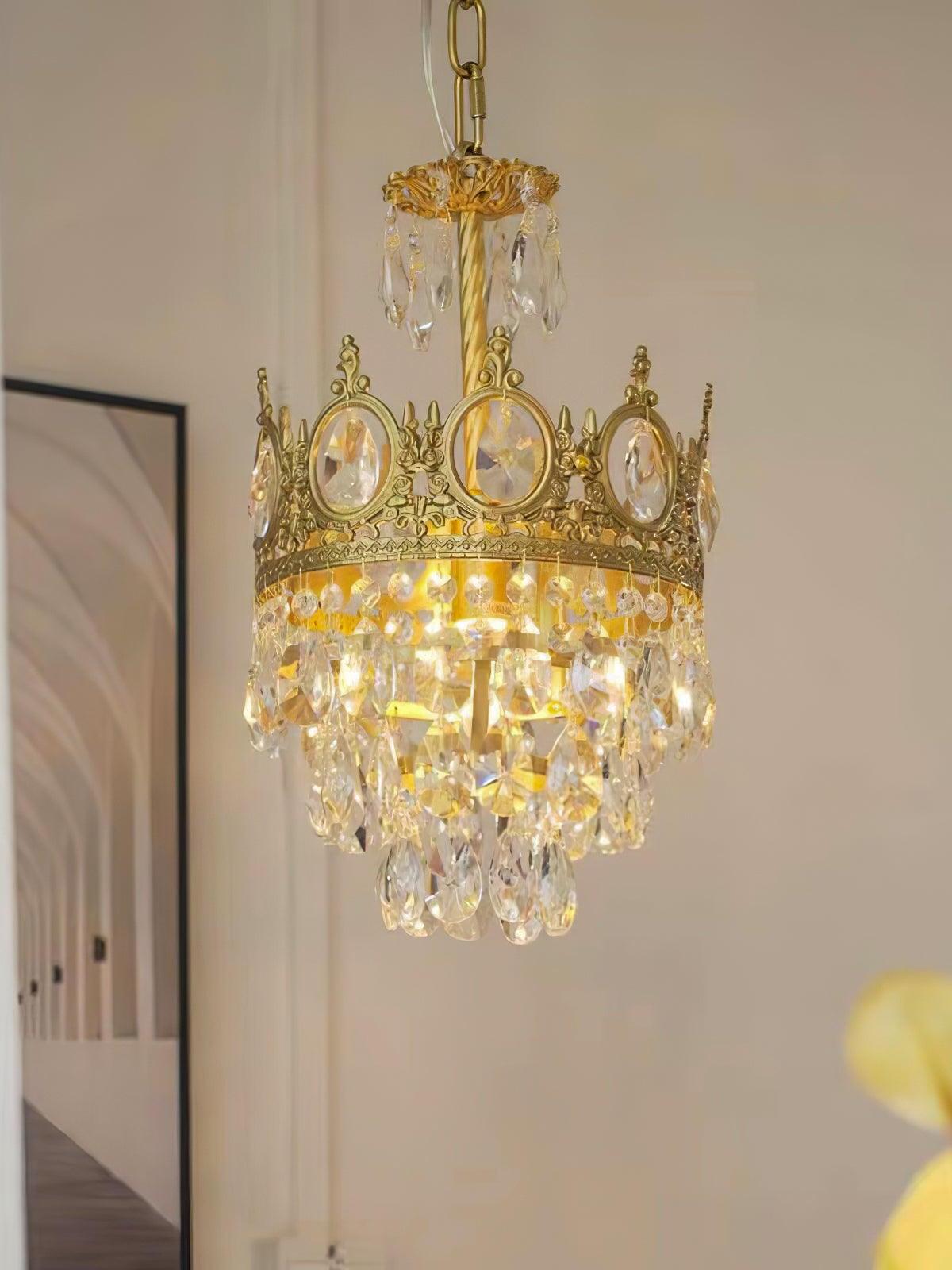 Gold-tone crystal chandelier illuminated by a light wall with a framed geometric artwork behind