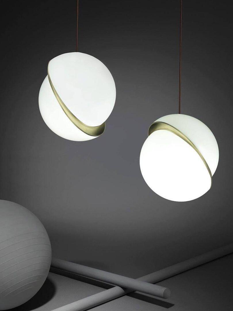 Two lit Crescent globes in different orientations against grey, with an exercise ball and pipes below