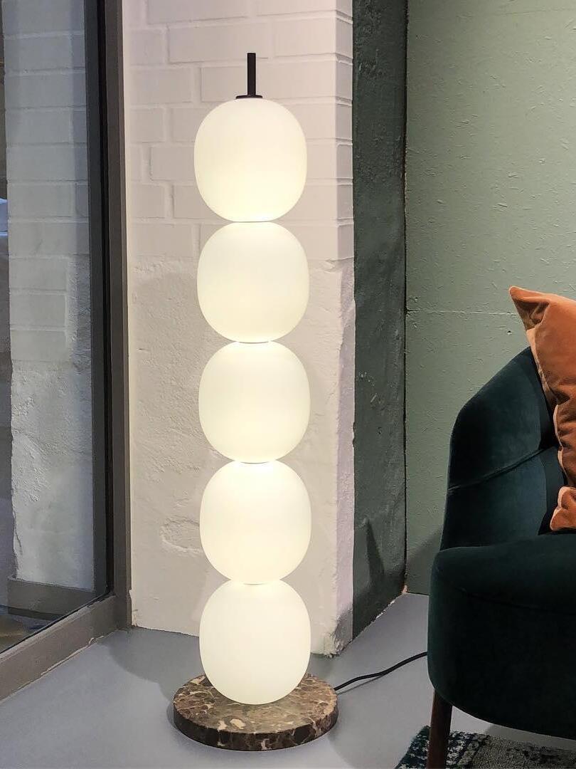 Illuminated globe column near dark armchair