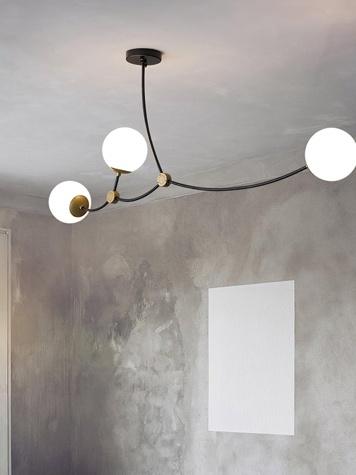 Three white globes on curved branches against a grey wall