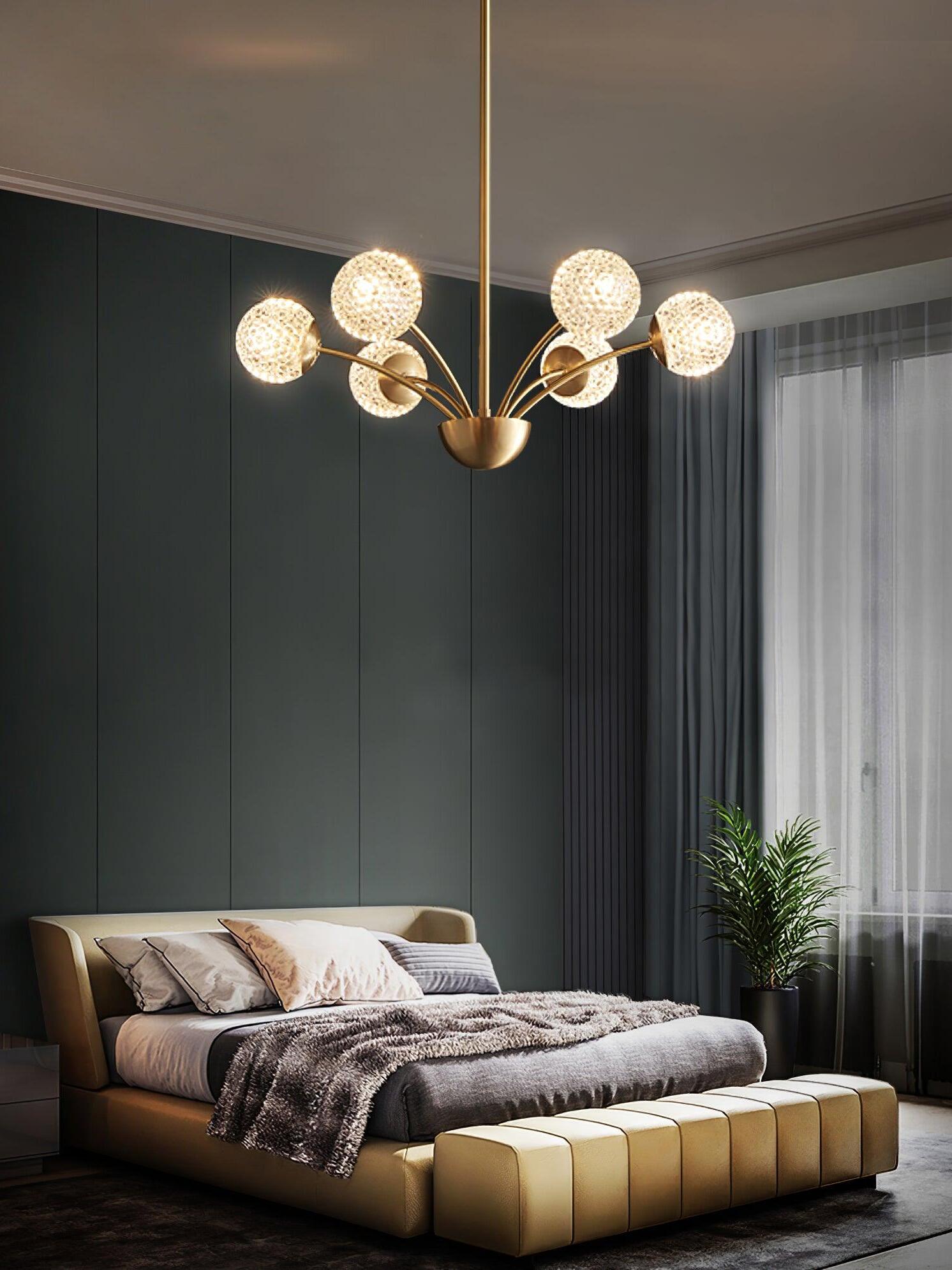 Six textured globes on brass-tone curved arms above a bed and tan bench beside green wall panels