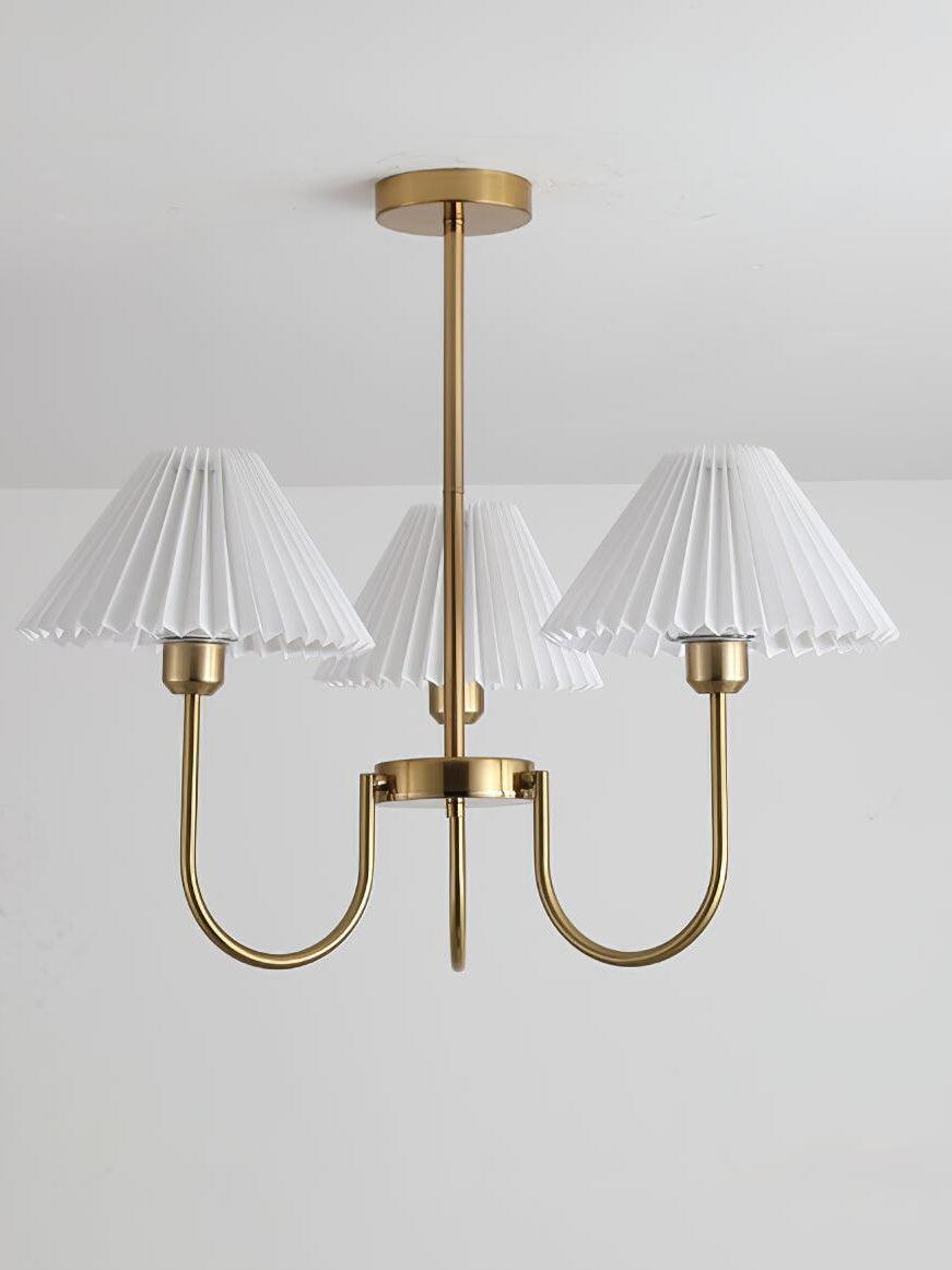 Unlit three-shade chandelier with a vertical rod against a pale wall