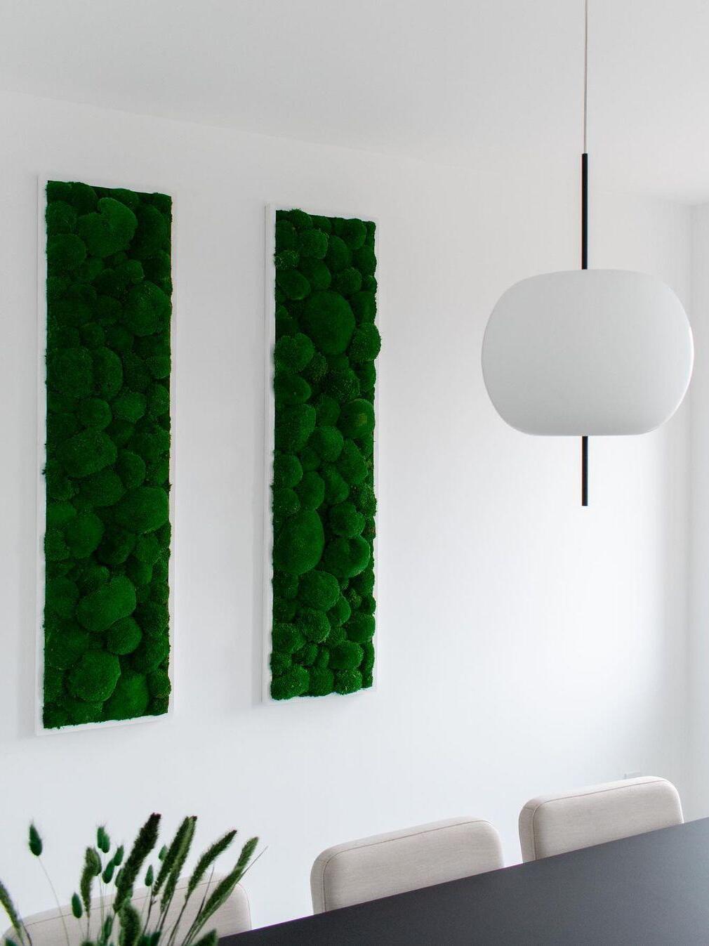 White glass pendant with a black stem beside green wall panels