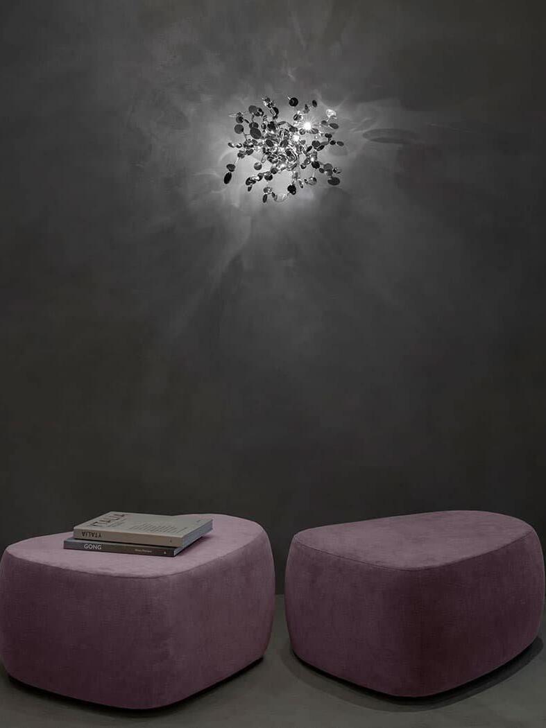Lit silver disc cluster above two purple ottomans