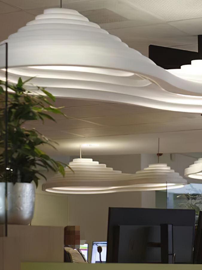 Close view of the stepped surface of an elongated white pendant, with other lamps in the background.